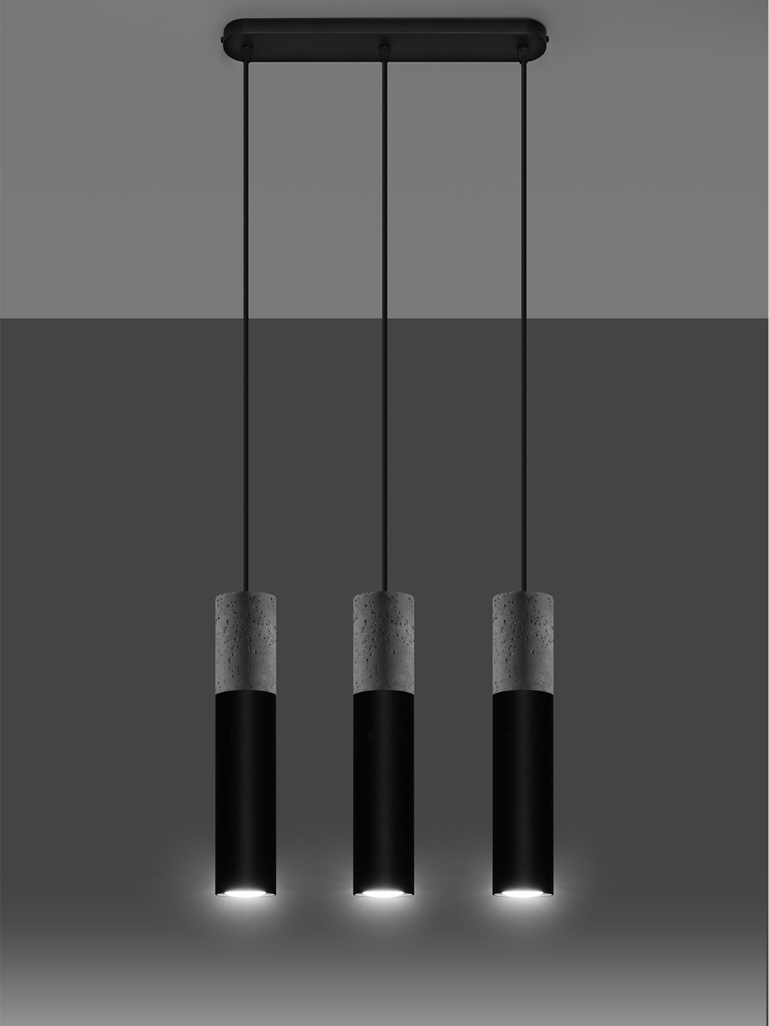 Potrójna czarna lampa wisząca z betonową oprawą na tle szarej ściany Potrójna czarna lampa wisząca z betonową oprawą na tle szarej ściany