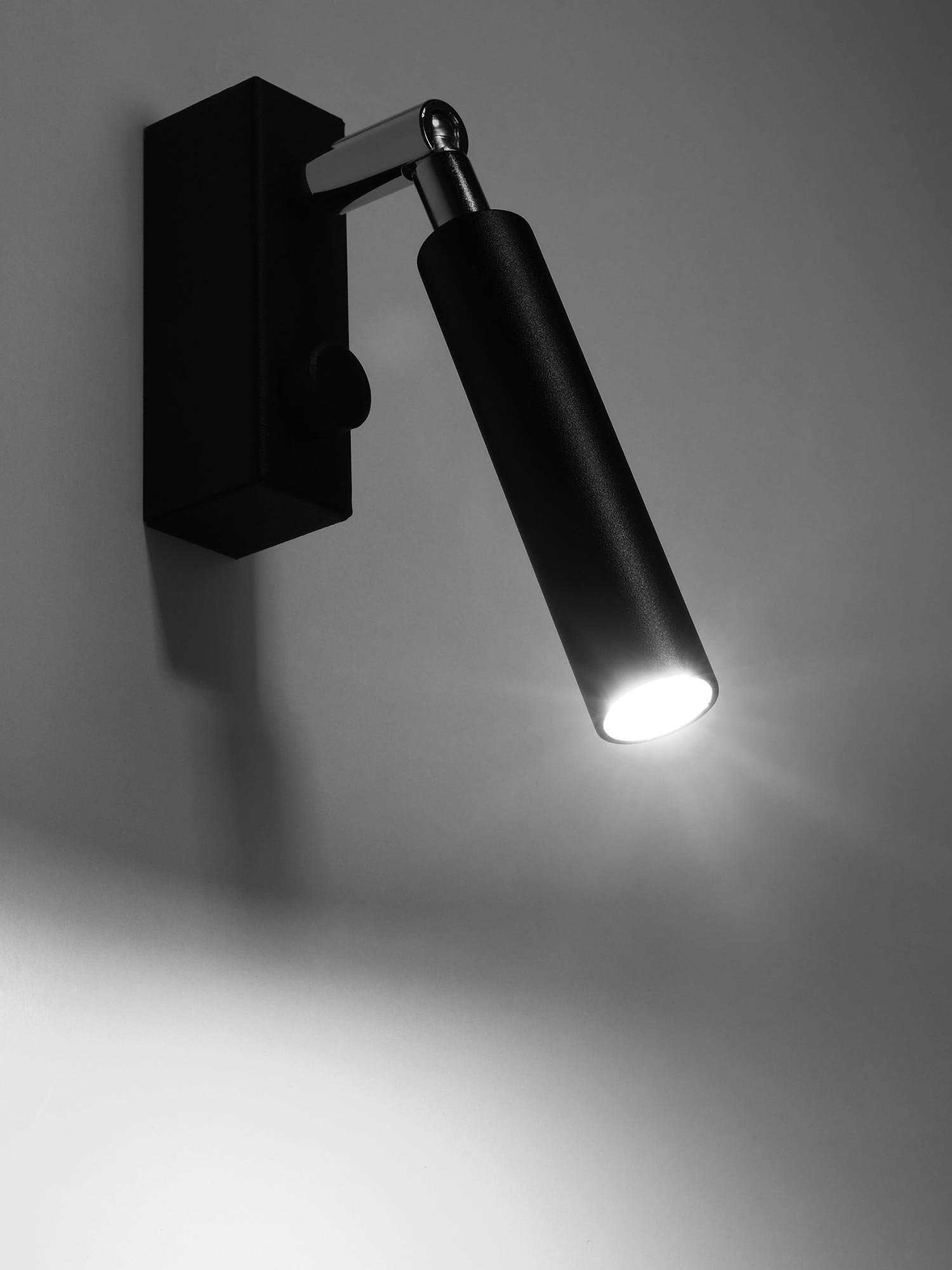 Kinkiet czarny LED z podłużnym reflektorem na białej ścianie Kinkiet czarny LED z podłużnym reflektorem na białej ścianie