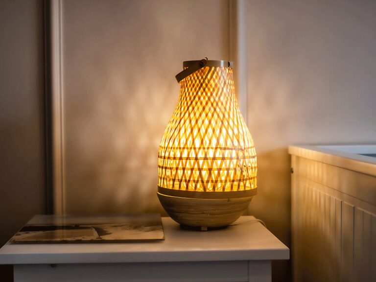 Pleciona lampa rattanowa na stoliku nocnym ve stylu boho