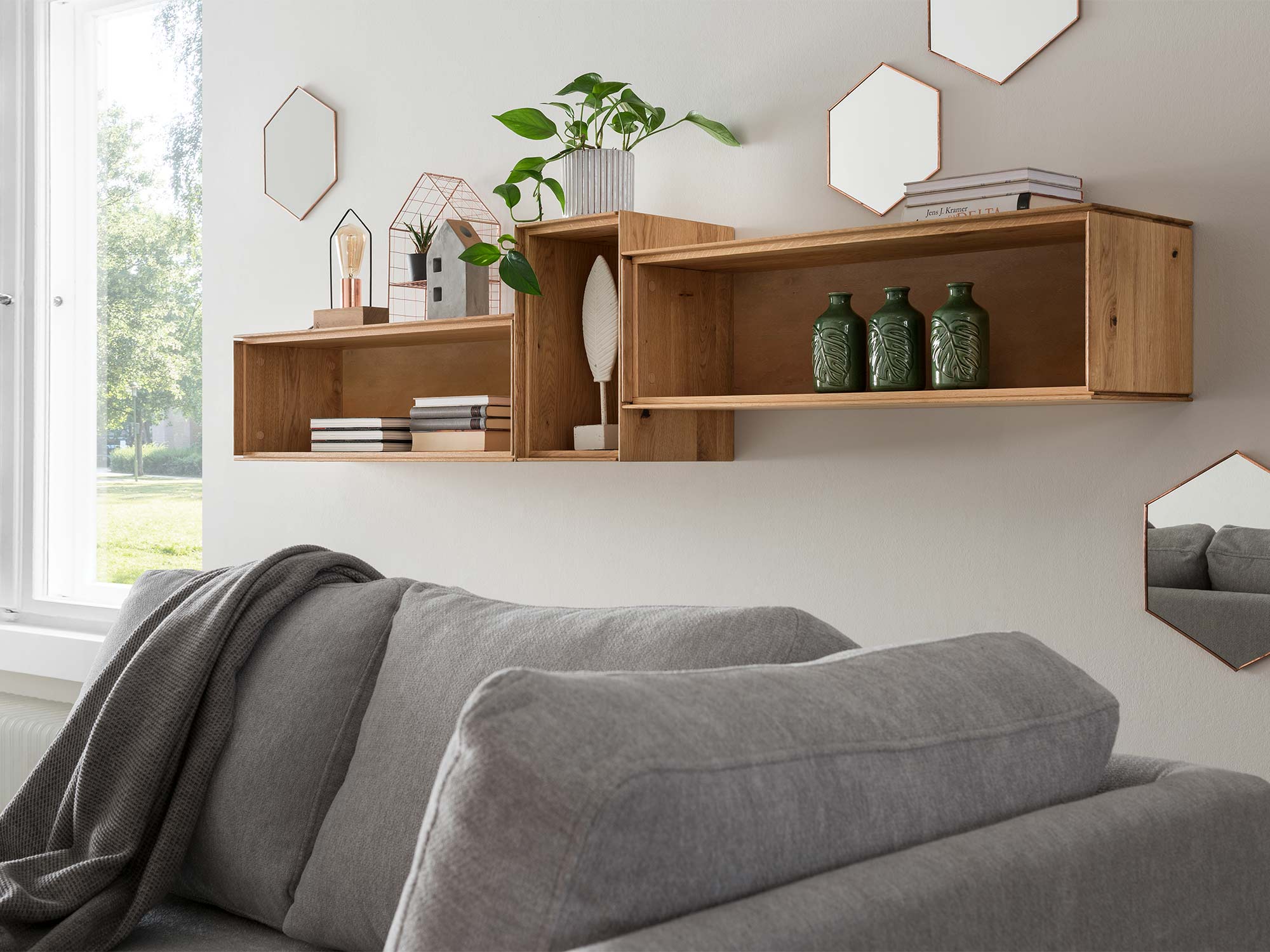 Drewniane półki i sofa w jasnym salonie w stylu boho