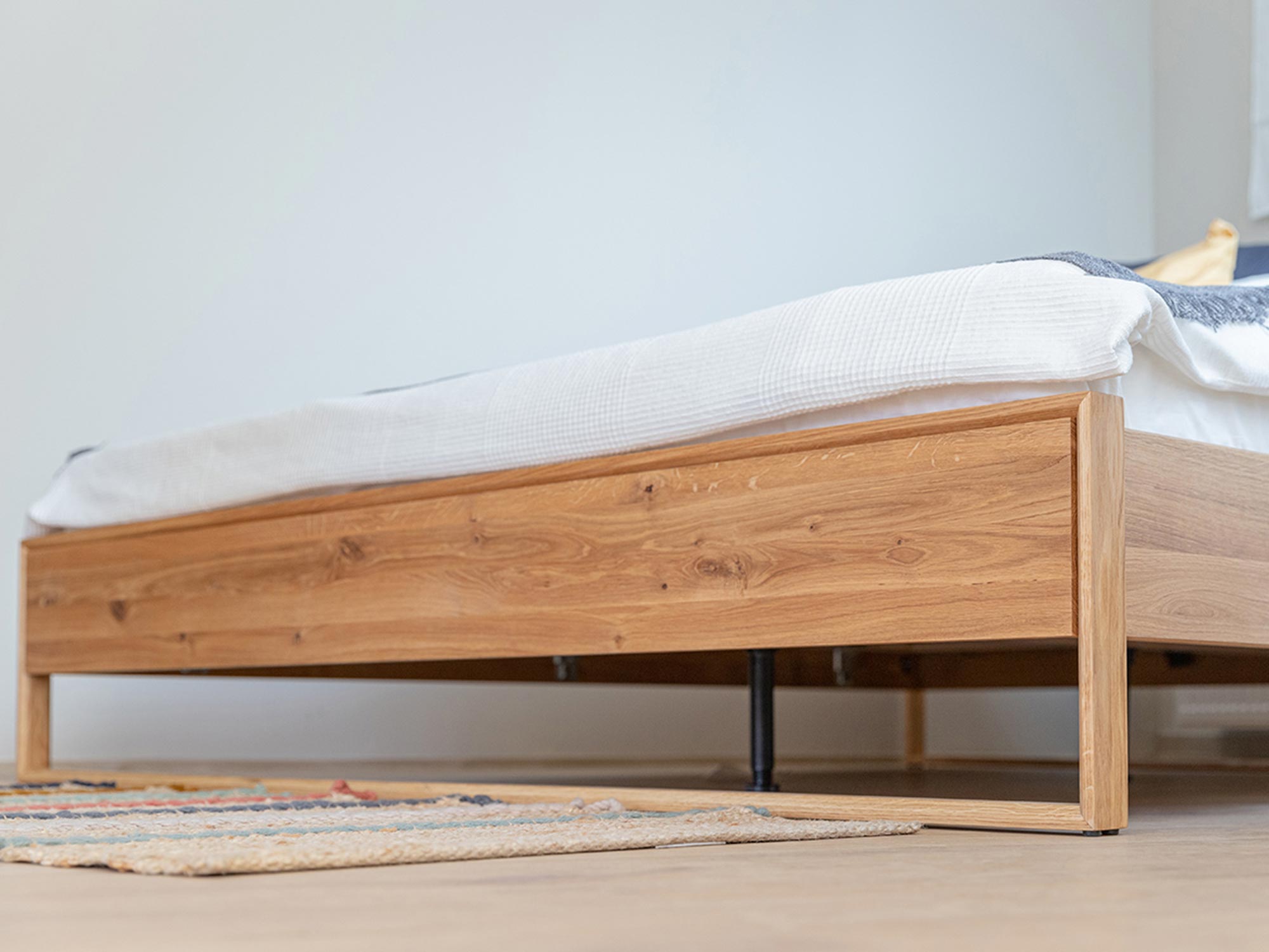 Niska rama łóżka z litego dębu, widok z boku