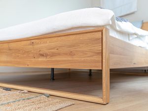Miniaturka 11 - Drewniane łóżko z niską ramą i łagodnie wygiętym zagłówkiem