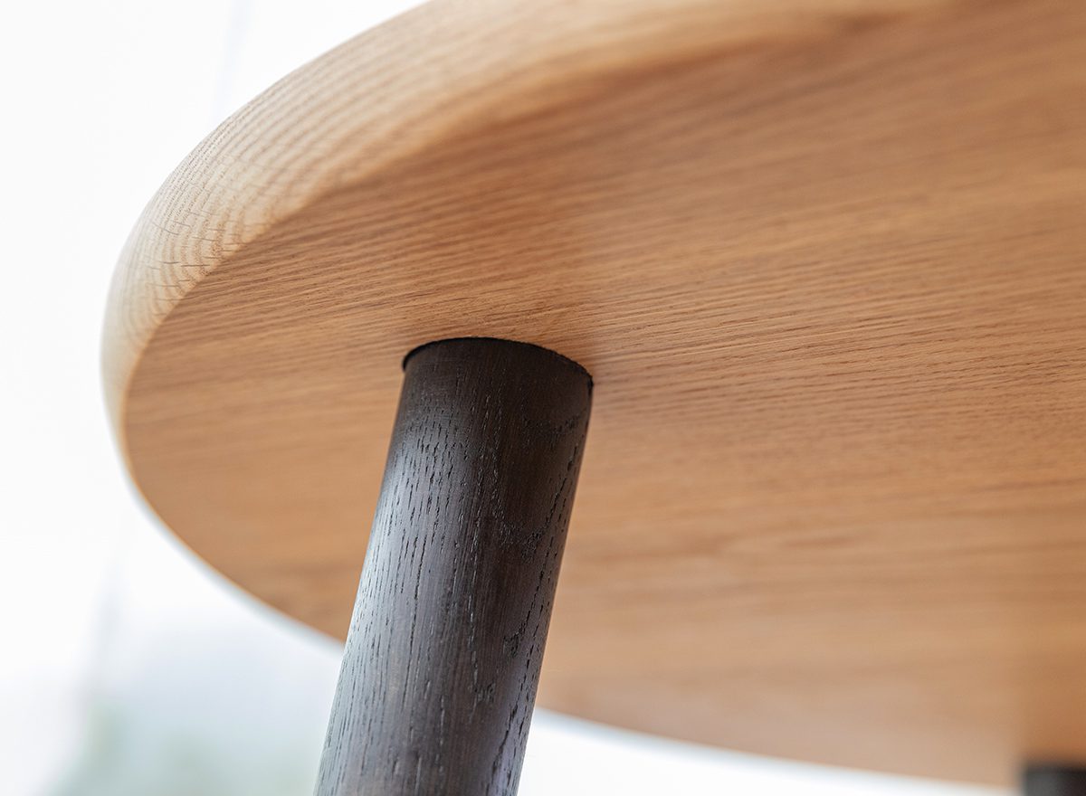 Ciemna metalowa noga osadzona w jasnym drewnianym blacie