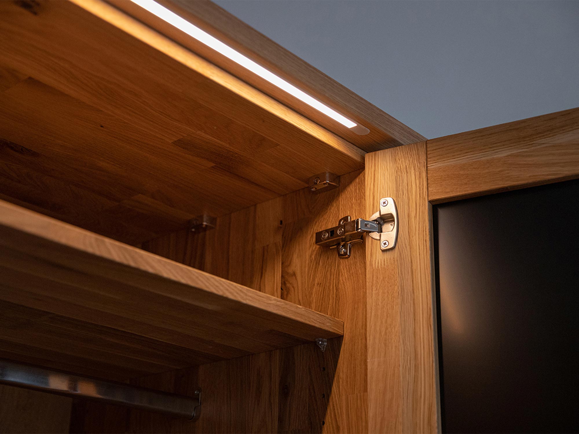 Zbliżenie na zawiasy w szafce z drewna z oświetleniem LED