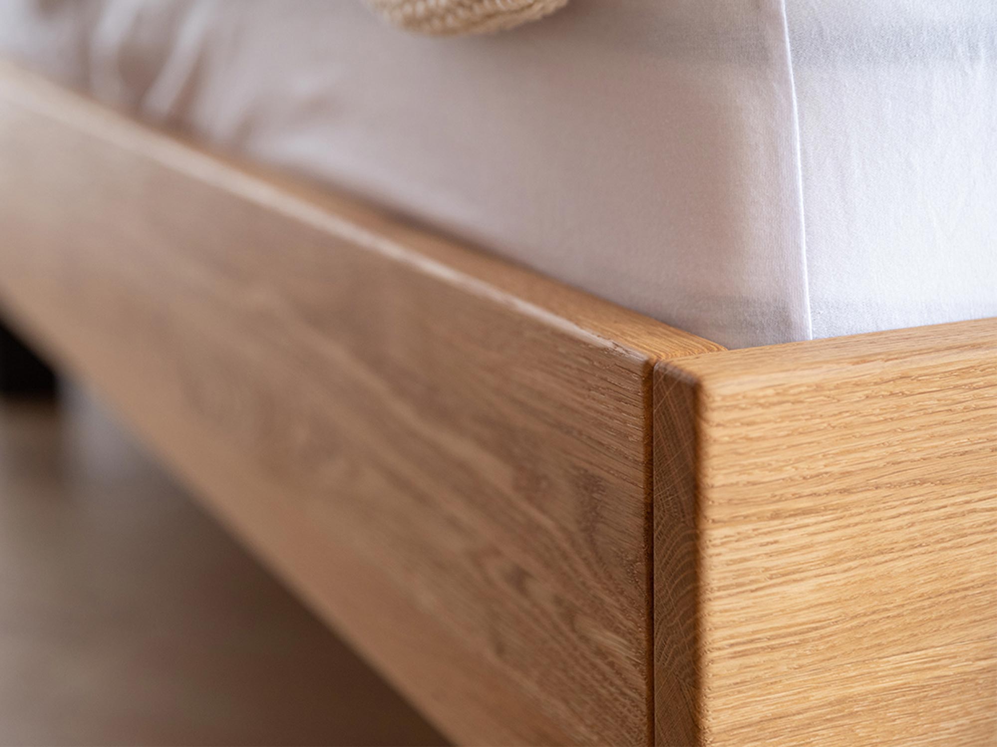 Detal łóżka z litego drewna z białym materacem