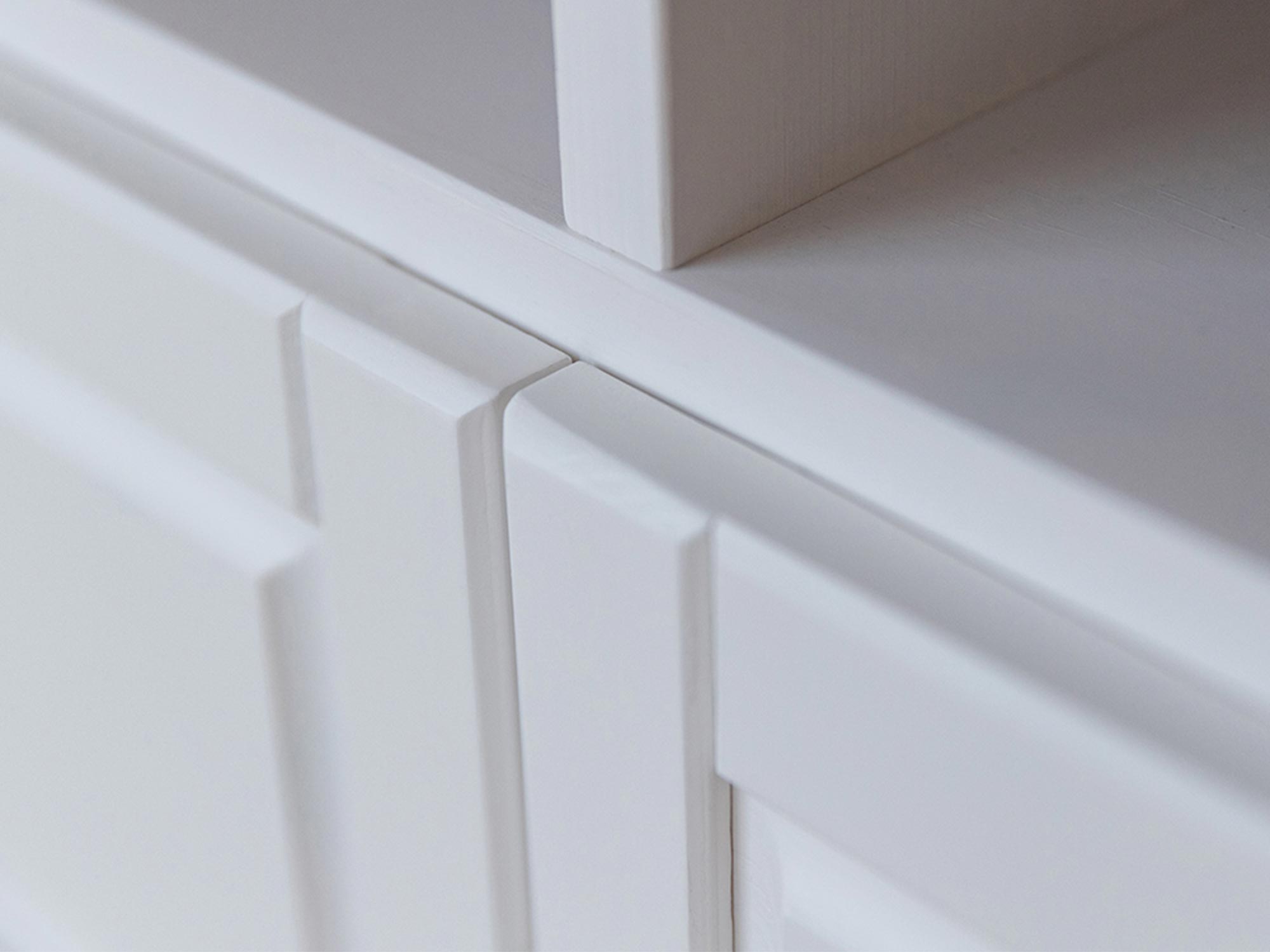 Zbliżenie na frezowane fronty szuflad w białej komodzie