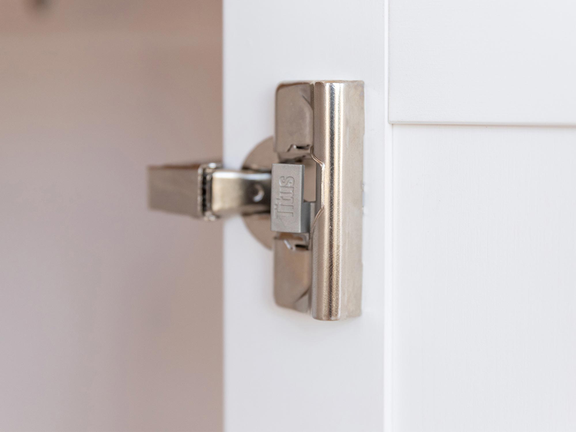 Zbliżenie na zawias metalowy montowany w białej witrynie