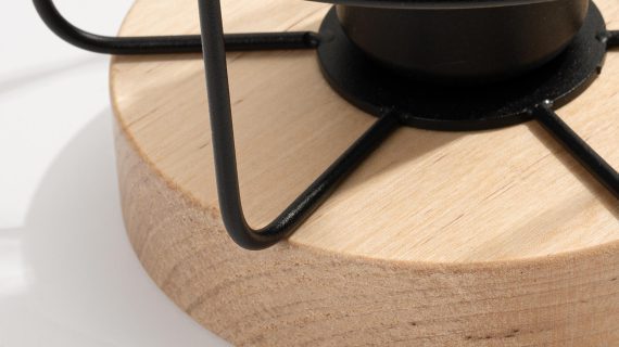 Miniaturka 3 - Zbliżenie na drewnianą podstawę lampy z metalowym drucianym kloszem