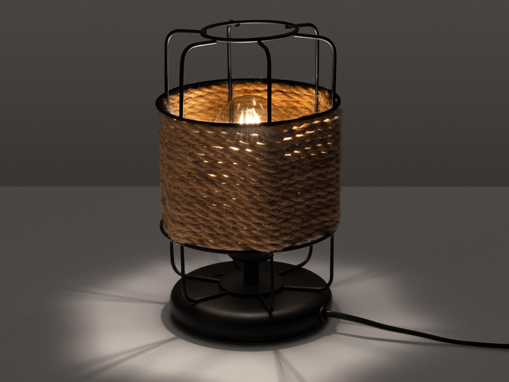 Wiklinowa lampa stołowa z włączonym światłem w ciemnym wnętrzu Wiklinowa lampa stołowa z włączonym światłem w ciemnym wnętrzu