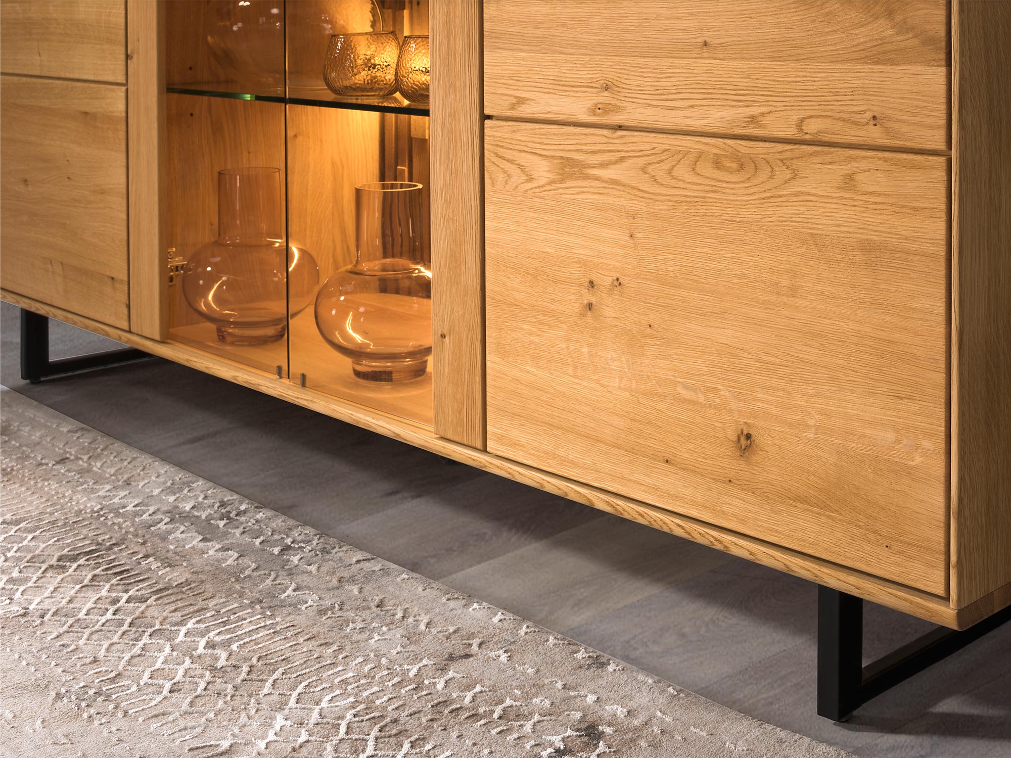 Detal komody drewnianej z podświetleniem i czarnymi nogami