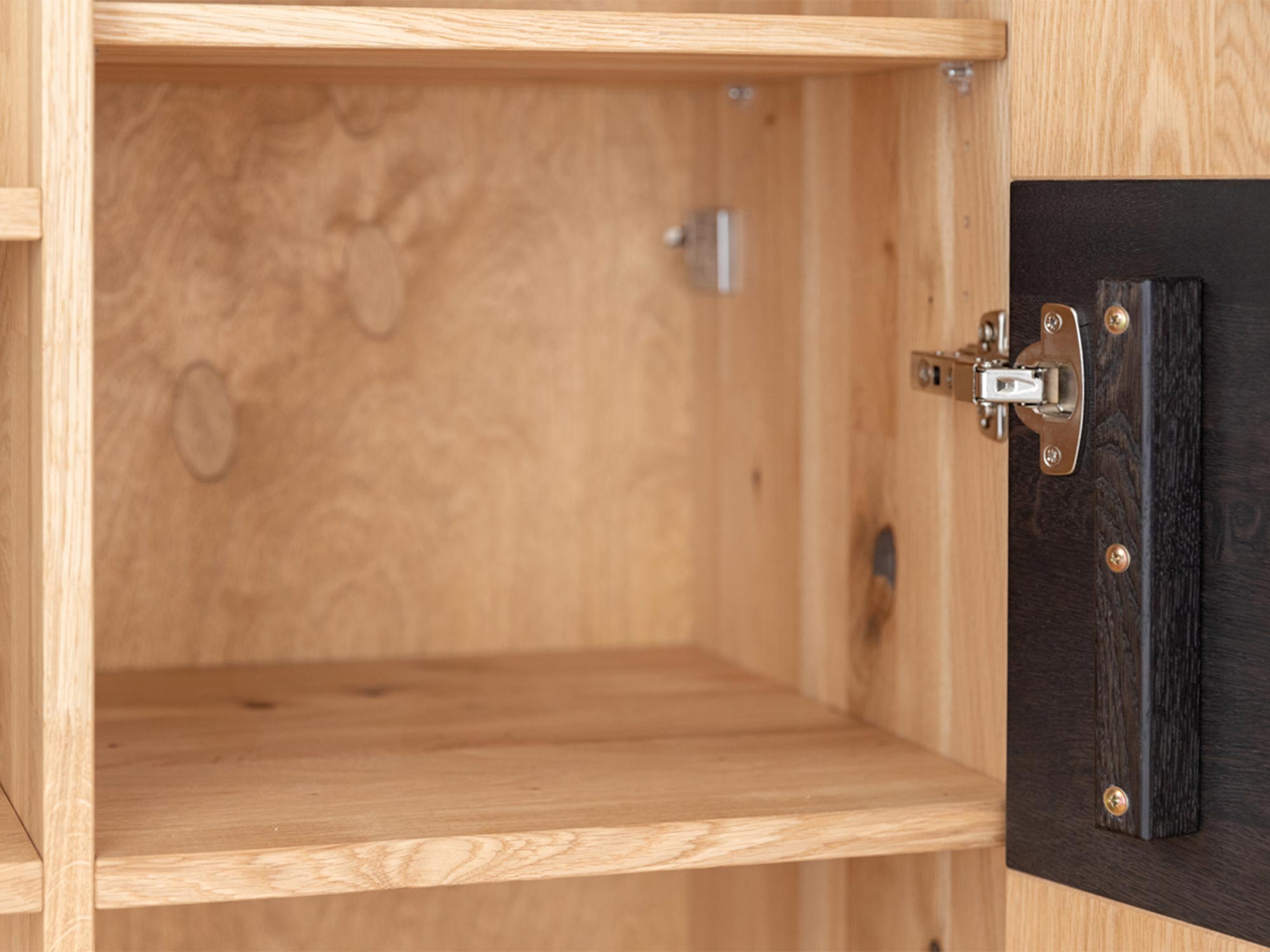 Detal solidnych zawiasów w drewnianej szafce RTV