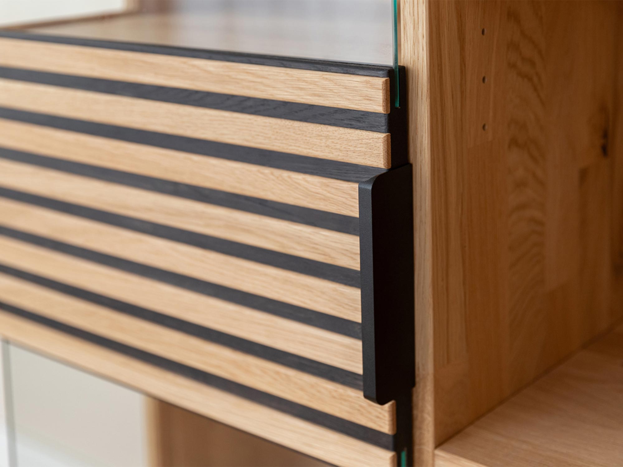 Detal wykończenia drewnianej witryny z czarnymi uchwytami