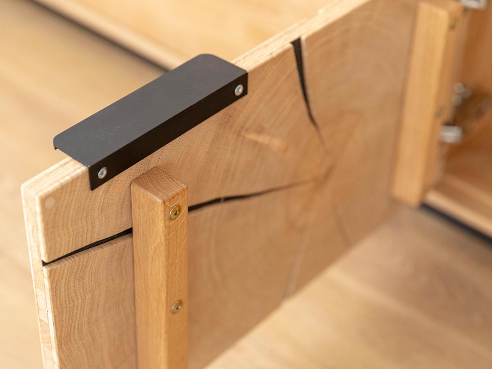 Detal łączenia drewna w nowoczesnej komodzie z metalowym czarnym uchwytem