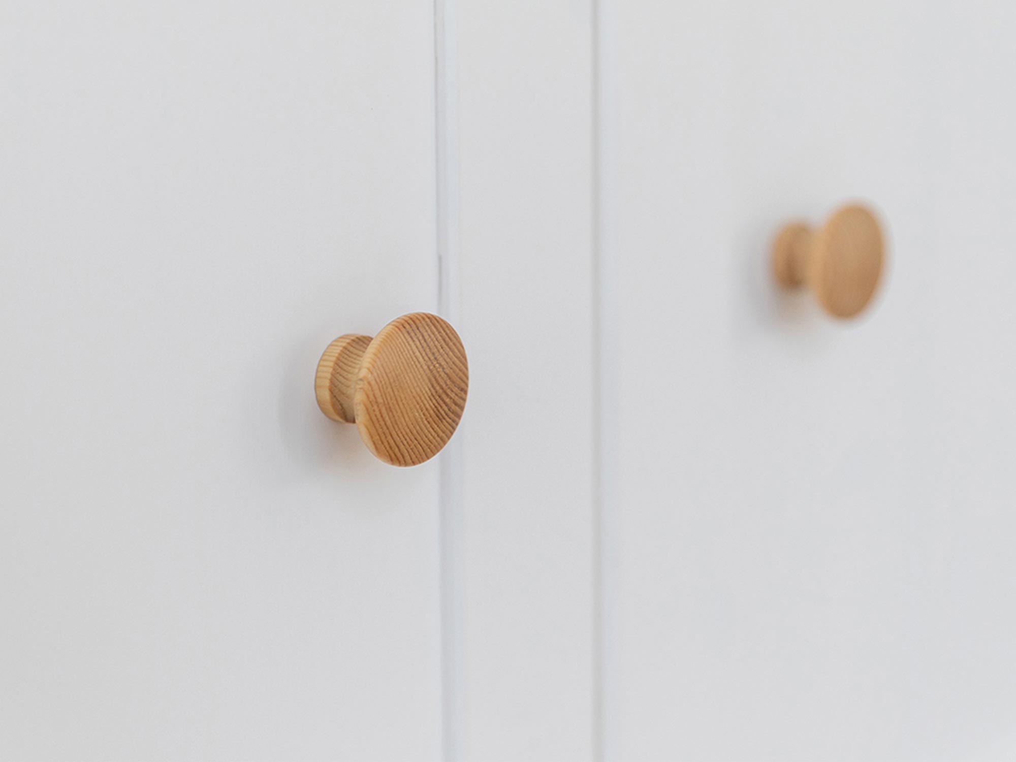 Klasyczna biała komoda z drewnianymi uchwytami