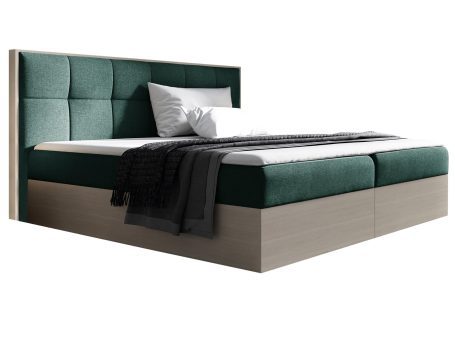 Zielone łóżko z tapicerowanym wezgłowiem i jasną drewnianą podstawą