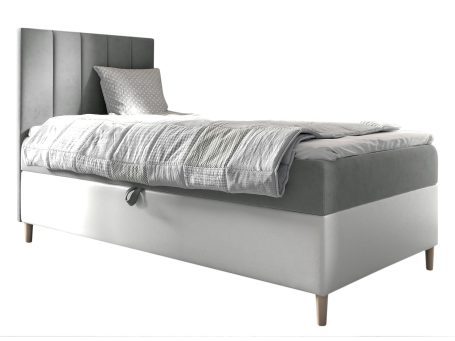 Szare łóżko z niskim zagłówkiem i grubym materacem.