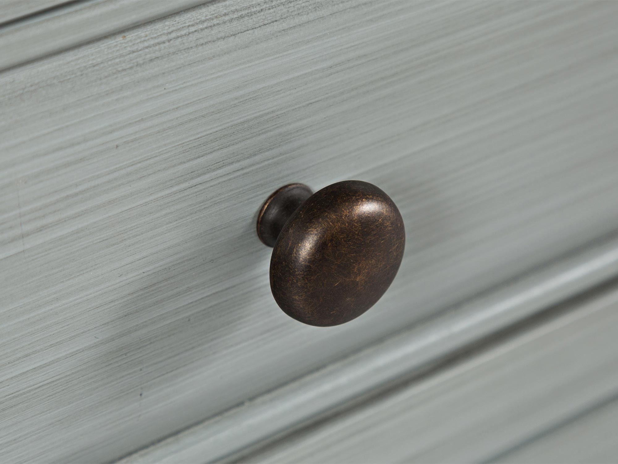 Szczegół wykończenia blatu szarej drewnianej komody w stylu klasycznym