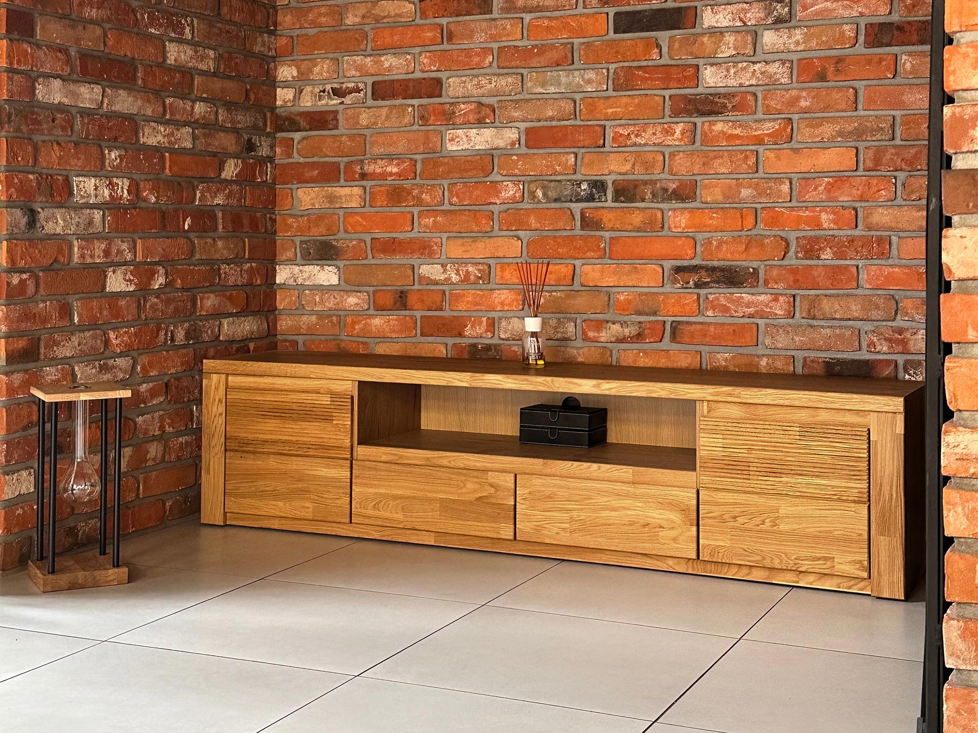 Komoda RTV pod czerwoną ceglaną ścianą w industrialnym wnętrzu
