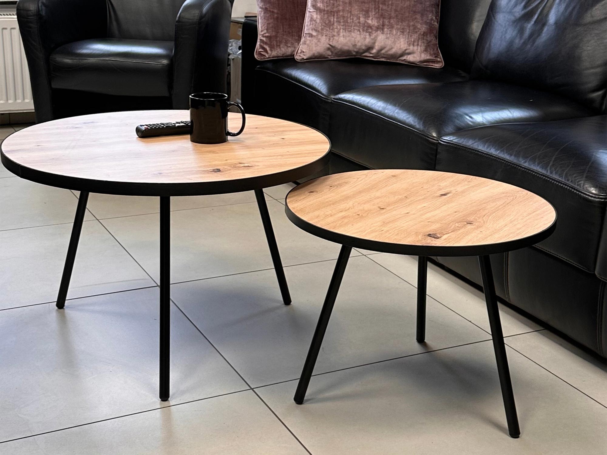 Komplet stolików w salonie z czarną sofą w tle