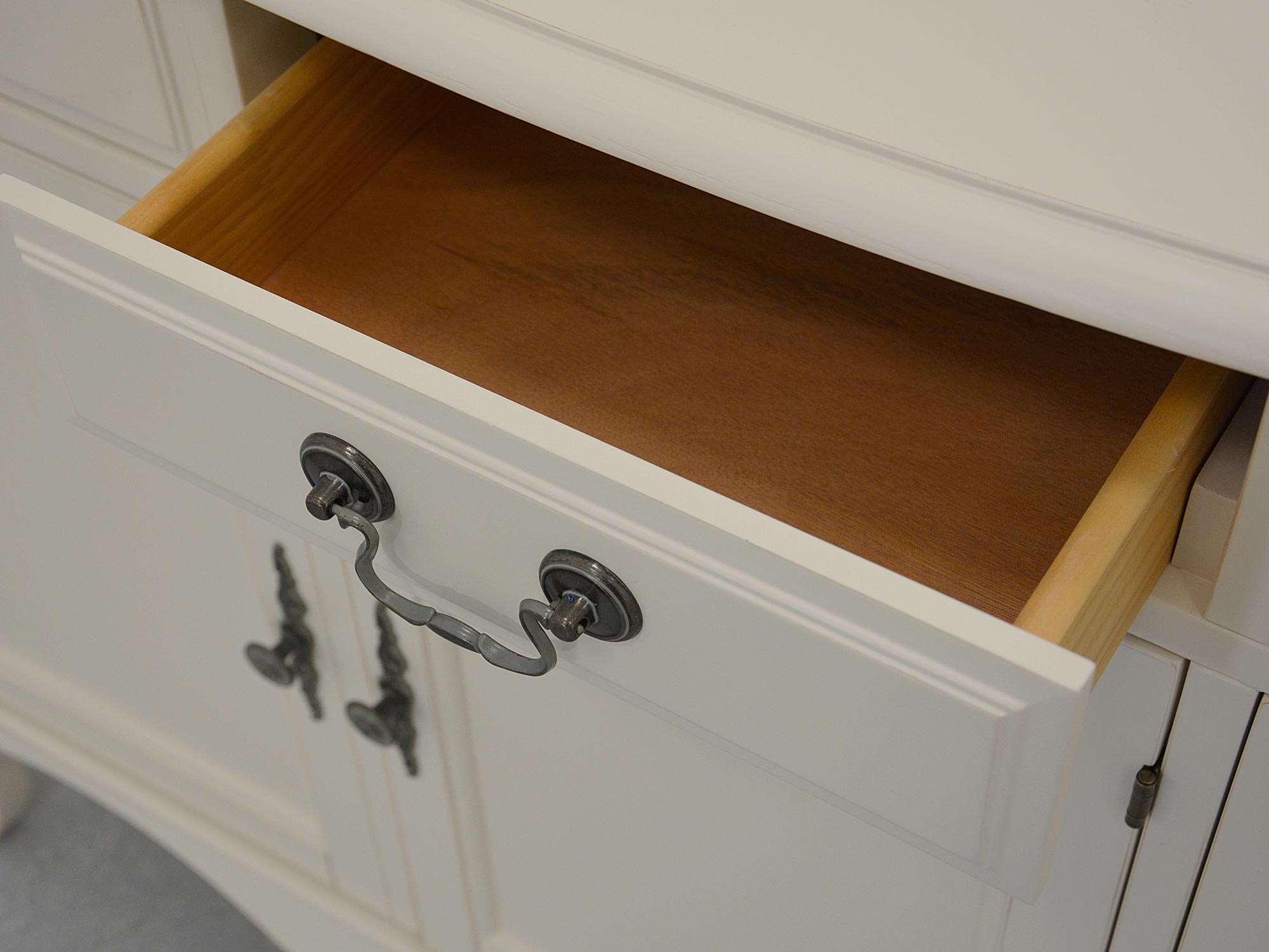 Szuflada z jasnego drewna wewnątrz klasycznej komody bielonej