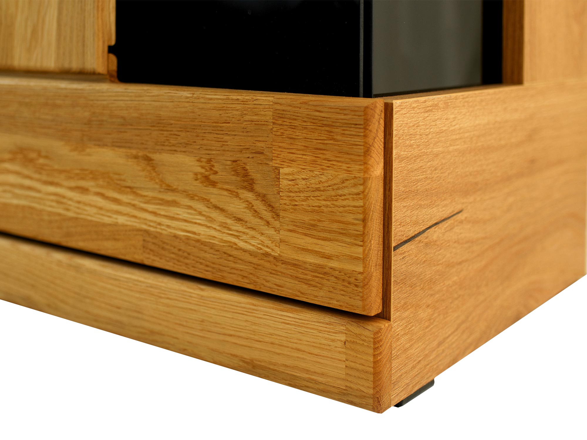 Zbliżenie na róg szafki z czarną szybą i frezowanym frontem