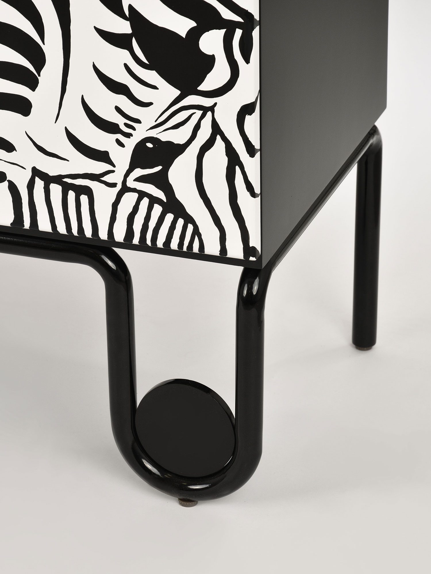 Detal komody z frontem w czarno-biały wzór zebry i metalową nogą