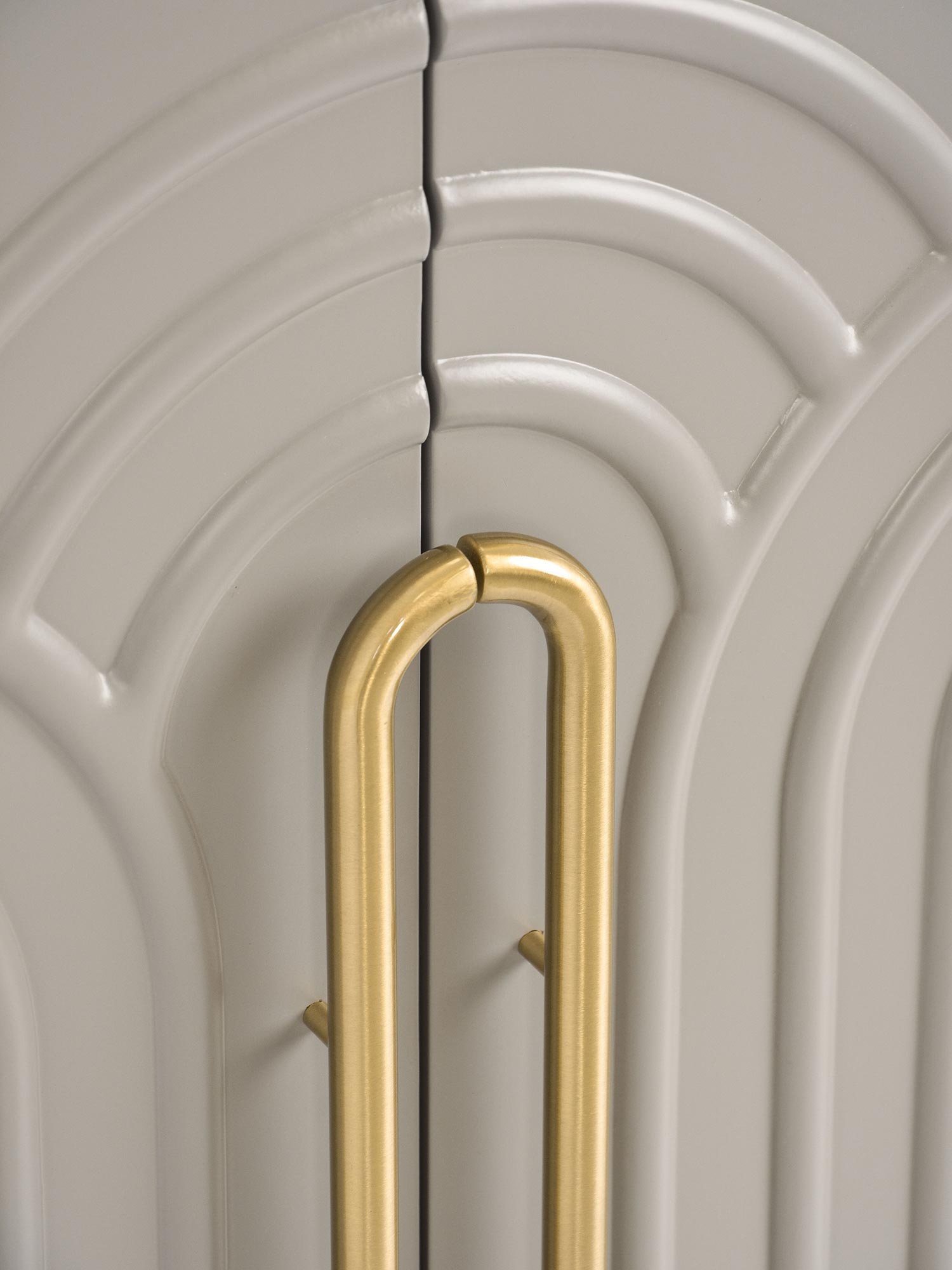 Jasnoszara komoda z ozdobnymi drzwiami i złotą rączką