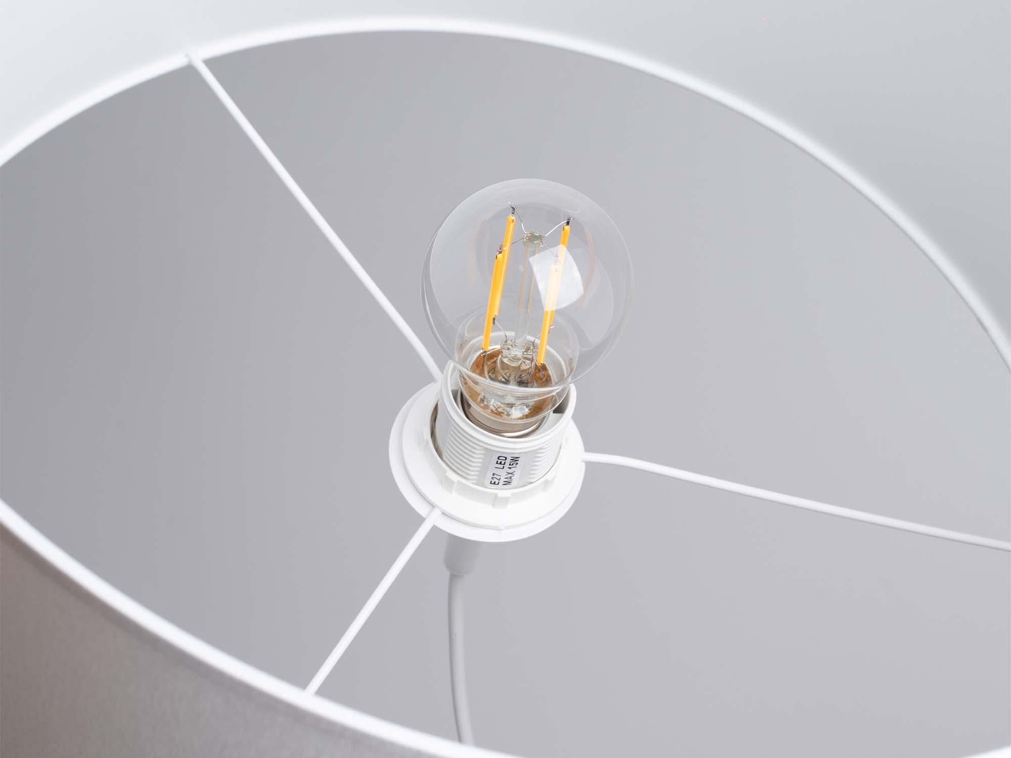 LED-Filament-Glühbirne in einer E27-Fassung innerhalb des Lampenschirms