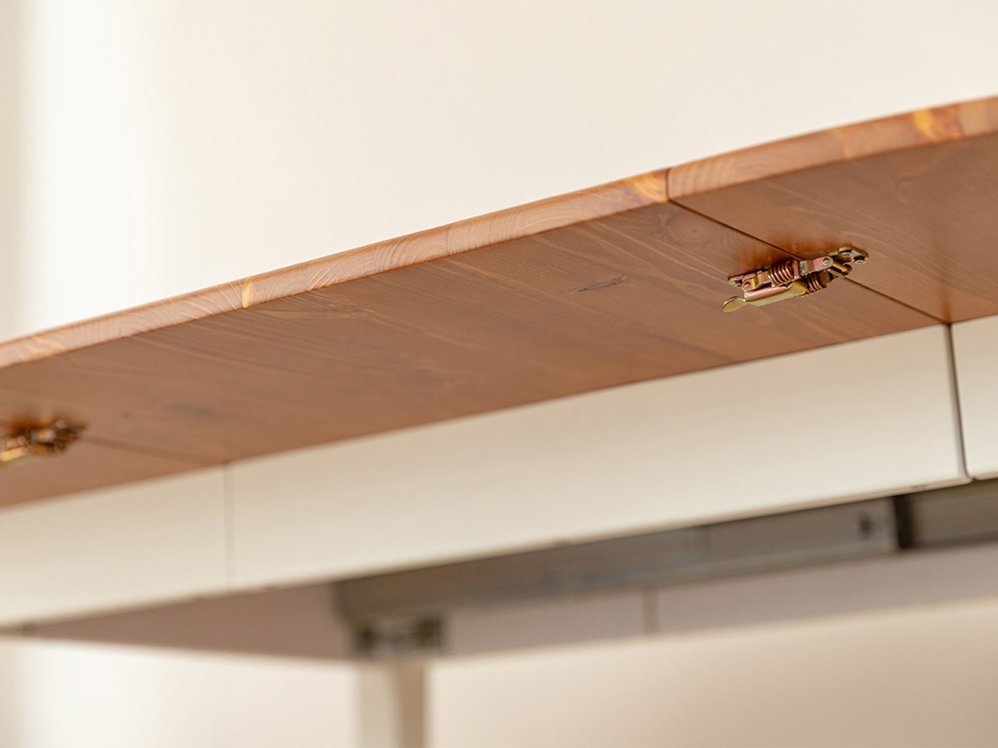 Detal mechanizmu blokady blatu stołu rozkładanego z zatrzaskami pod spodem