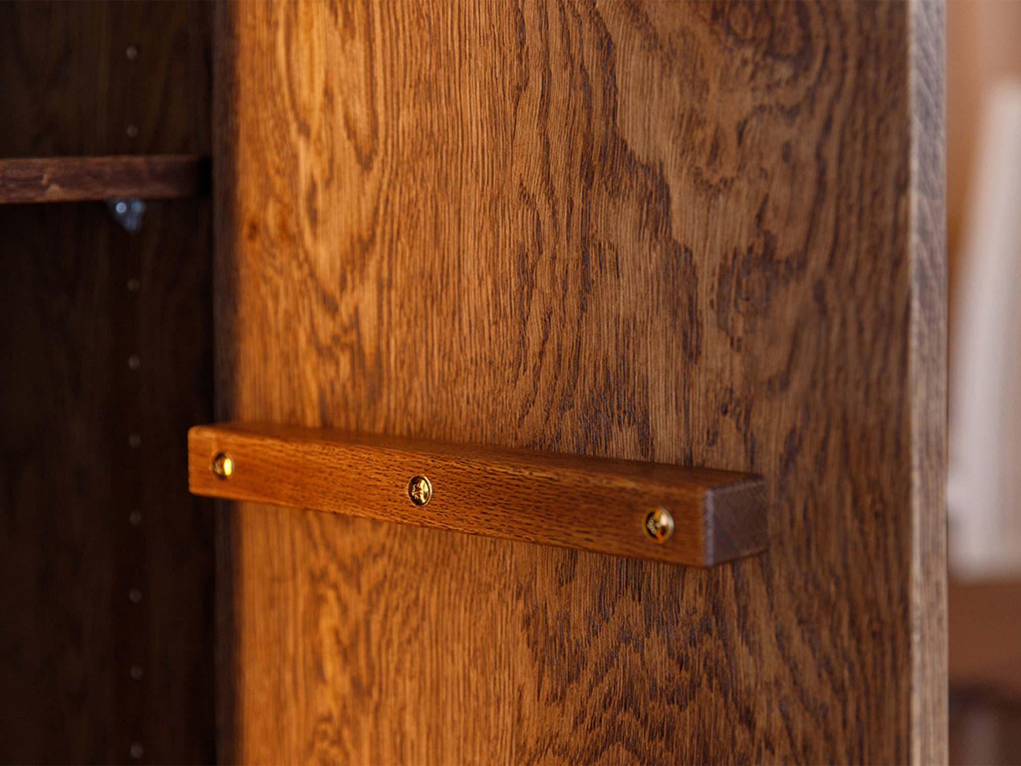 Detal drewnianego uchwytu drzwi witryny tabacco z usłojeniem dębu
