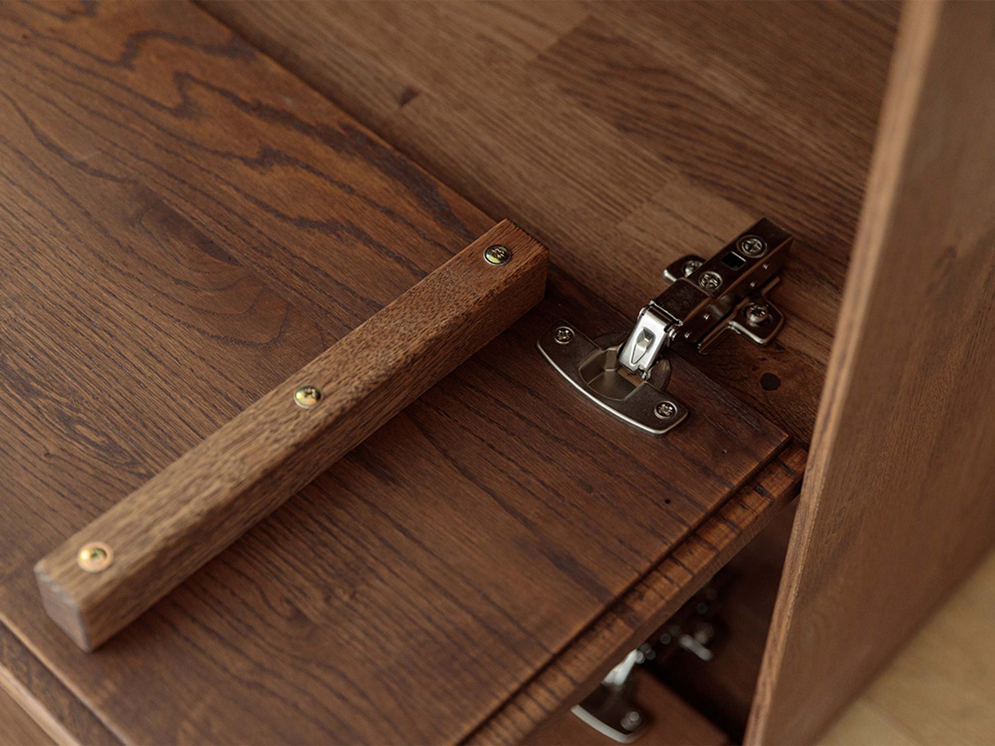 Detal klapy komody tabacco z drewnianym uchwytem i zawiasem