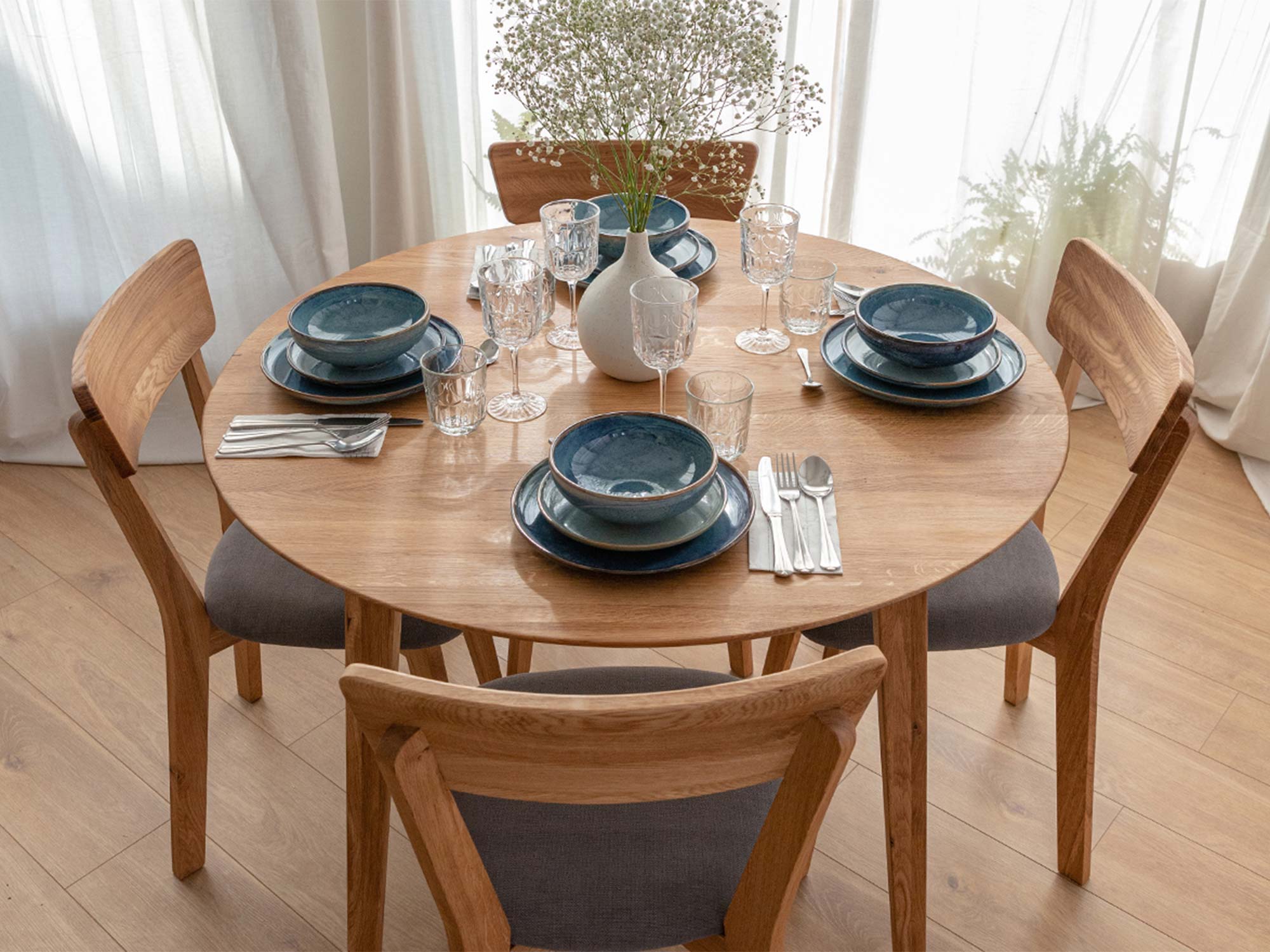 Stół dębowy okrągły w aranżacji jadalni z niebieską zastawą