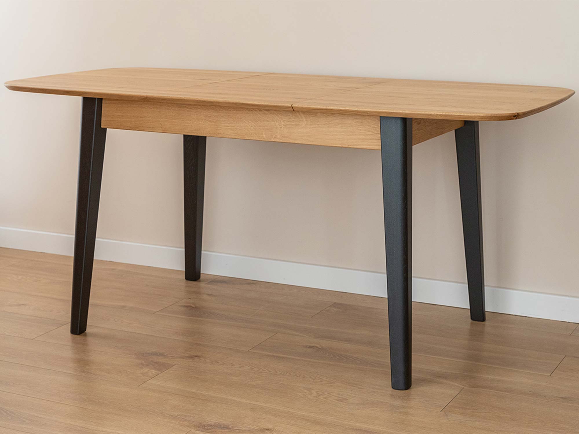 Dębowy stół rozkładany z ciemnymi nogami rozłożony z wkładką