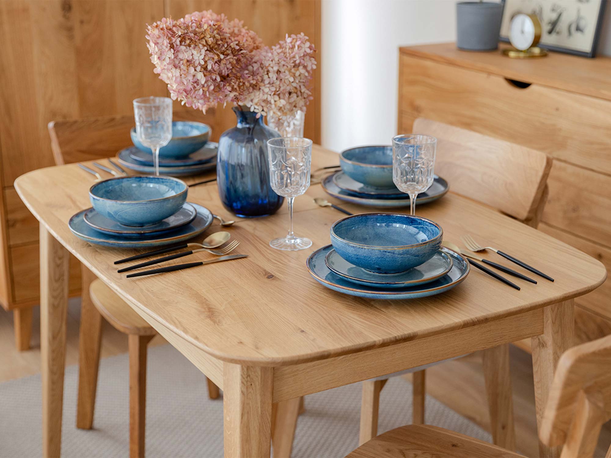 Stół dębowy jasny rozkładany w aranżacji jadalni z niebieską zastawą