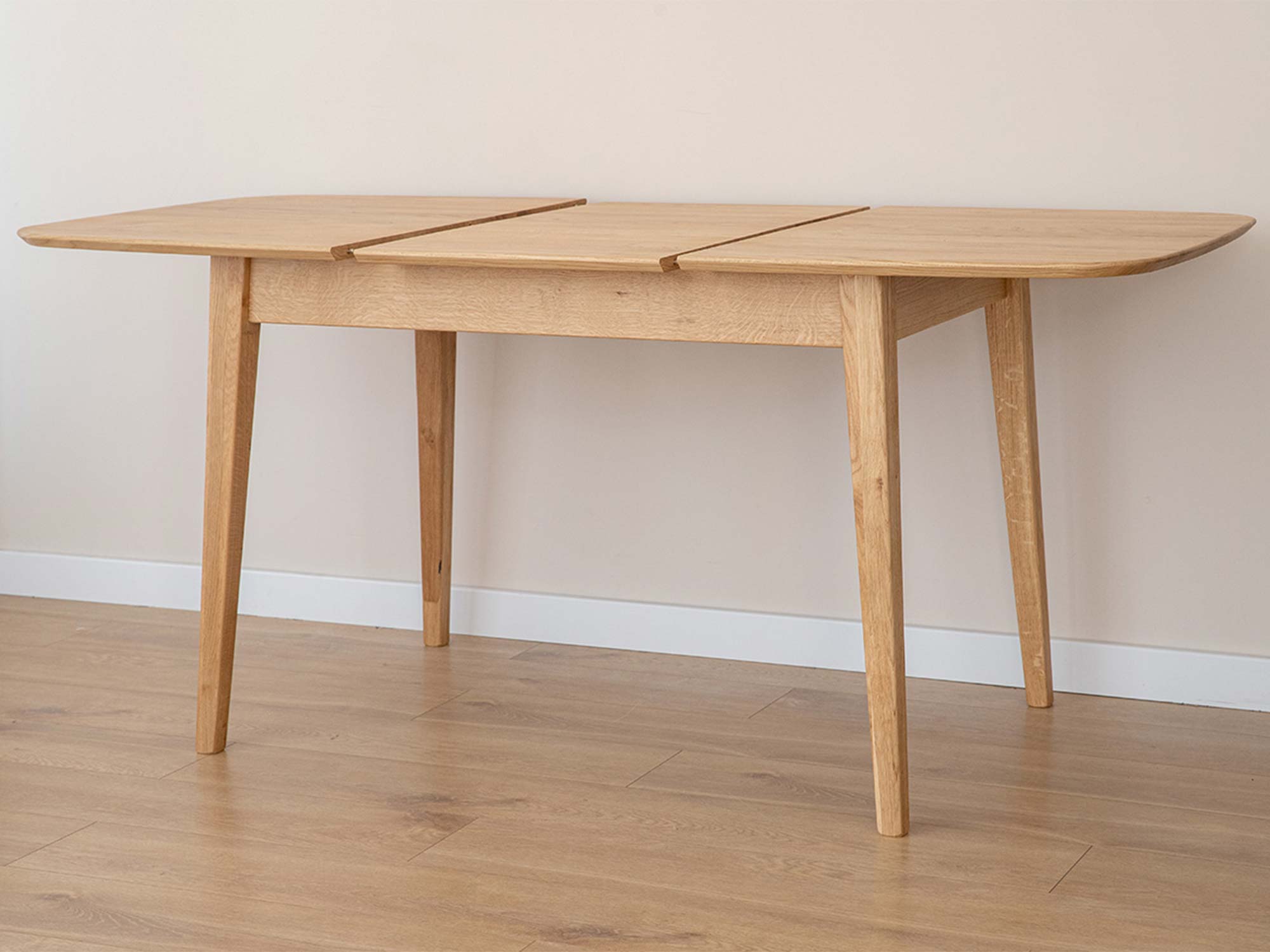 Stół dębowy jasny rozłożony z wkładką na drewnianej podłodze