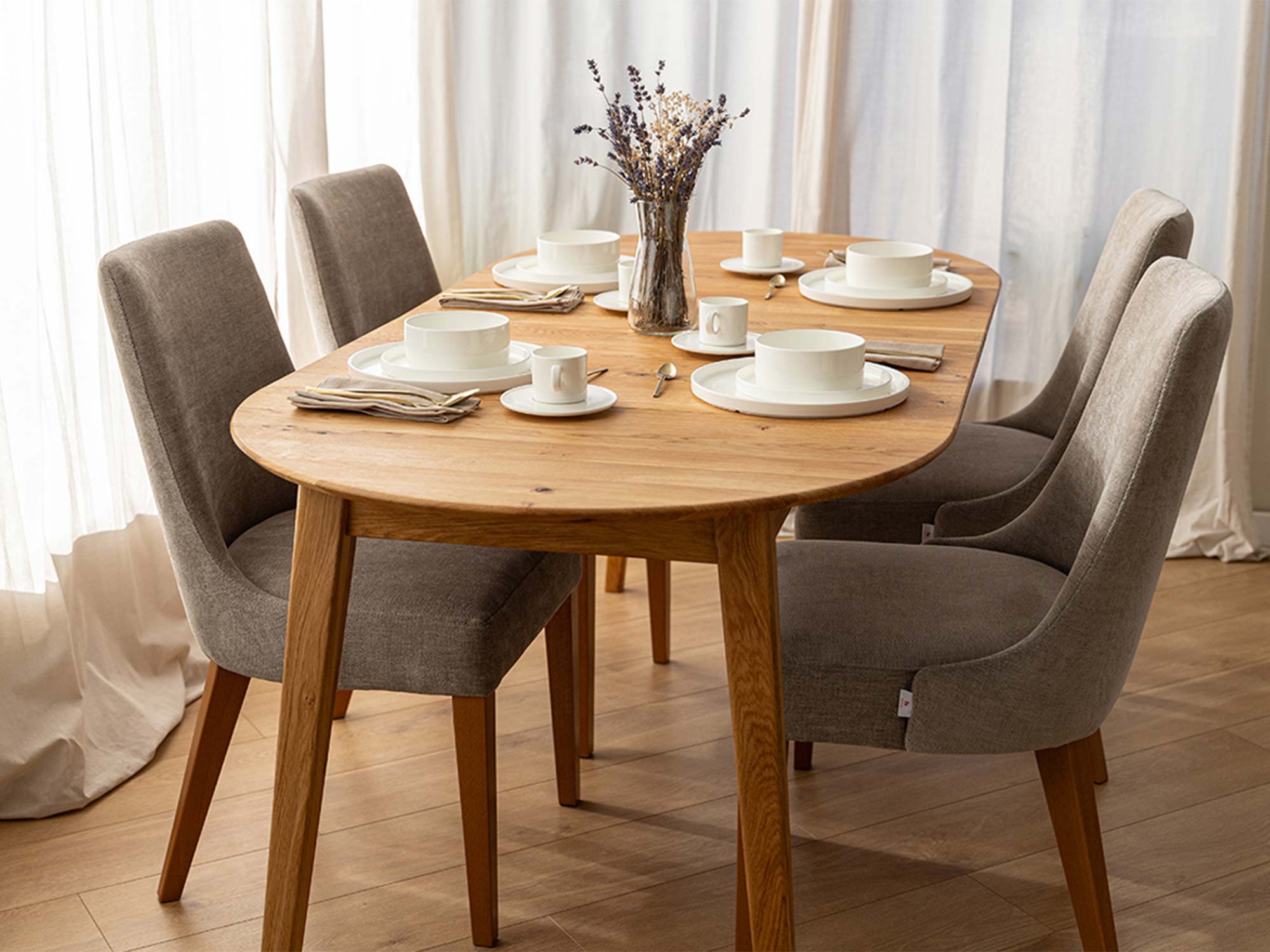 Owalny stół dębowy złożony w aranżacji jadalni z krzesłami tapicerowanymi