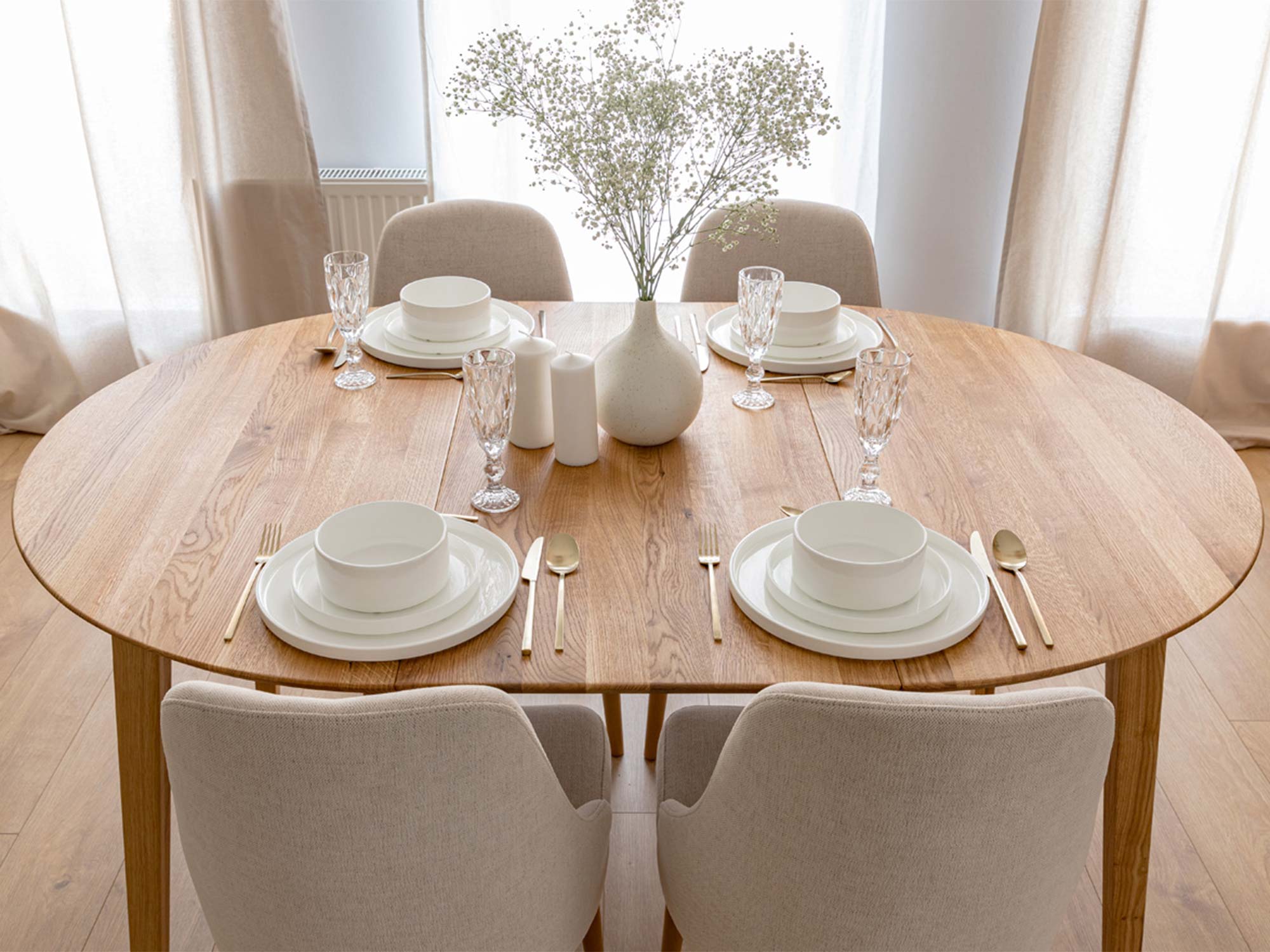 Dębowy stół owalny w aranżacji jadalni z beżowymi krzesłami tapicerowanymi