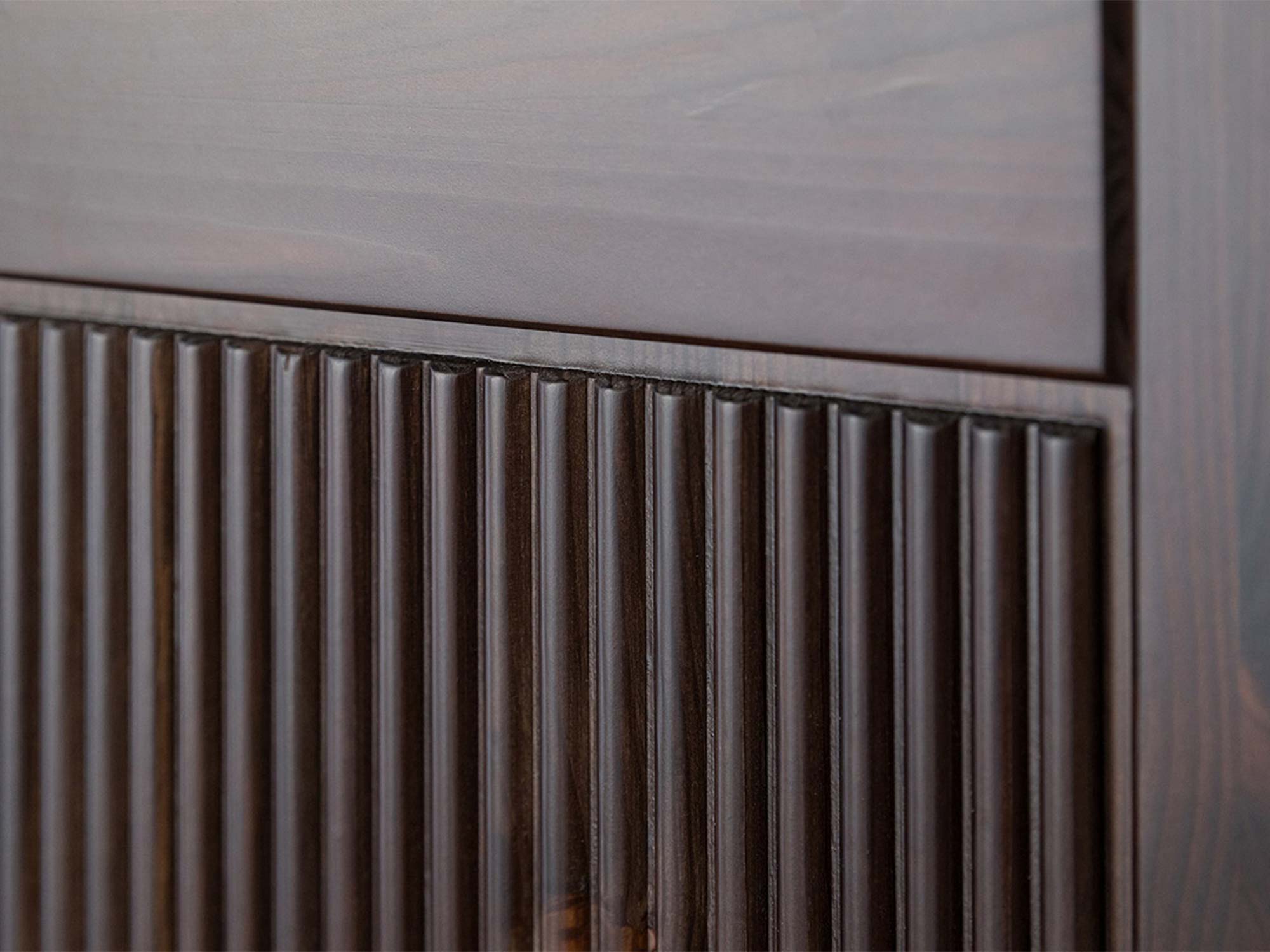 Detal ryflowanego frontu drzwi szafki dwudrzwiowej drewnianej ciemnobrązowej zbliżenie