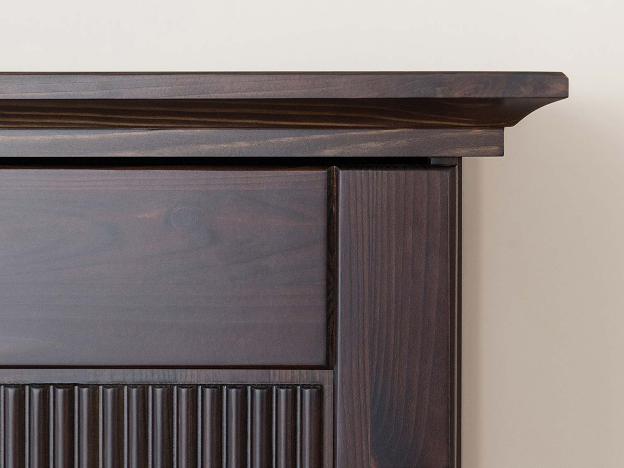 Detal ryflowanego panelu drzwi szafy czterodrzwiowej drewnianej ciemnobrązowej zbliżenie