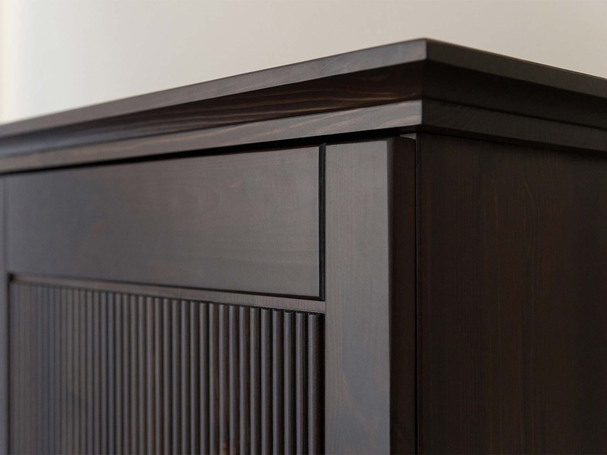 Detal usłojenia drewna szafy trójdrzwiowej ciemnobrązowej z ryflowanym panelem