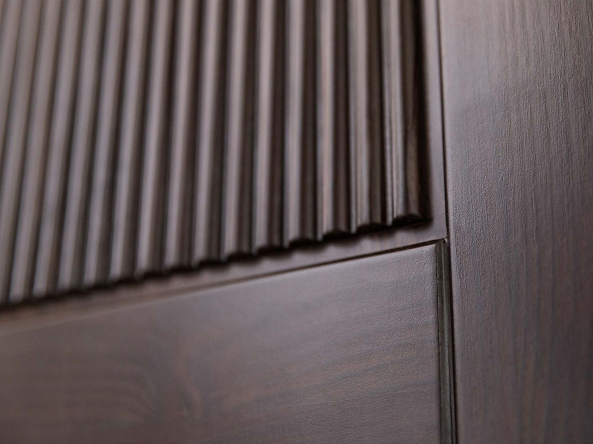 Detal cokołu szafy drewnianej ciemnobrązowej z ryflowanym frontem