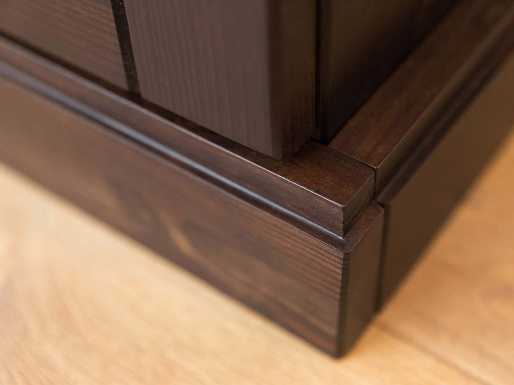 Detal górnego gzymsu szafy trójdrzwiowej drewnianej ciemnobrązowej zbliżenie