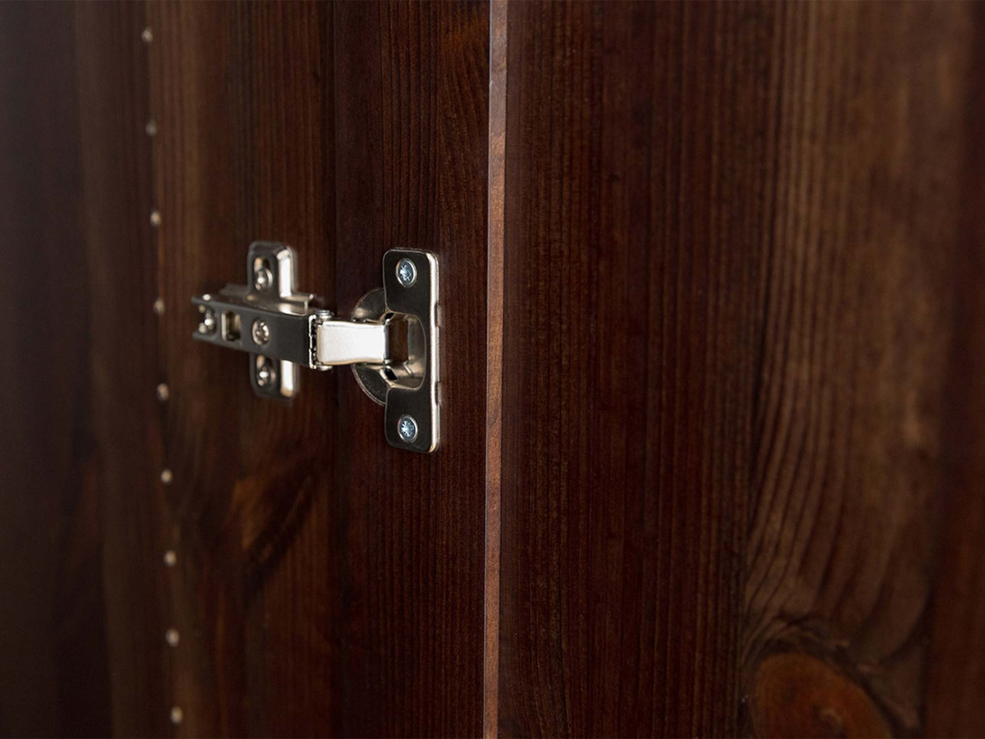 Detal zawiasu drzwi szafki dwudrzwiowej drewnianej ciemnobrązowej zbliżenie