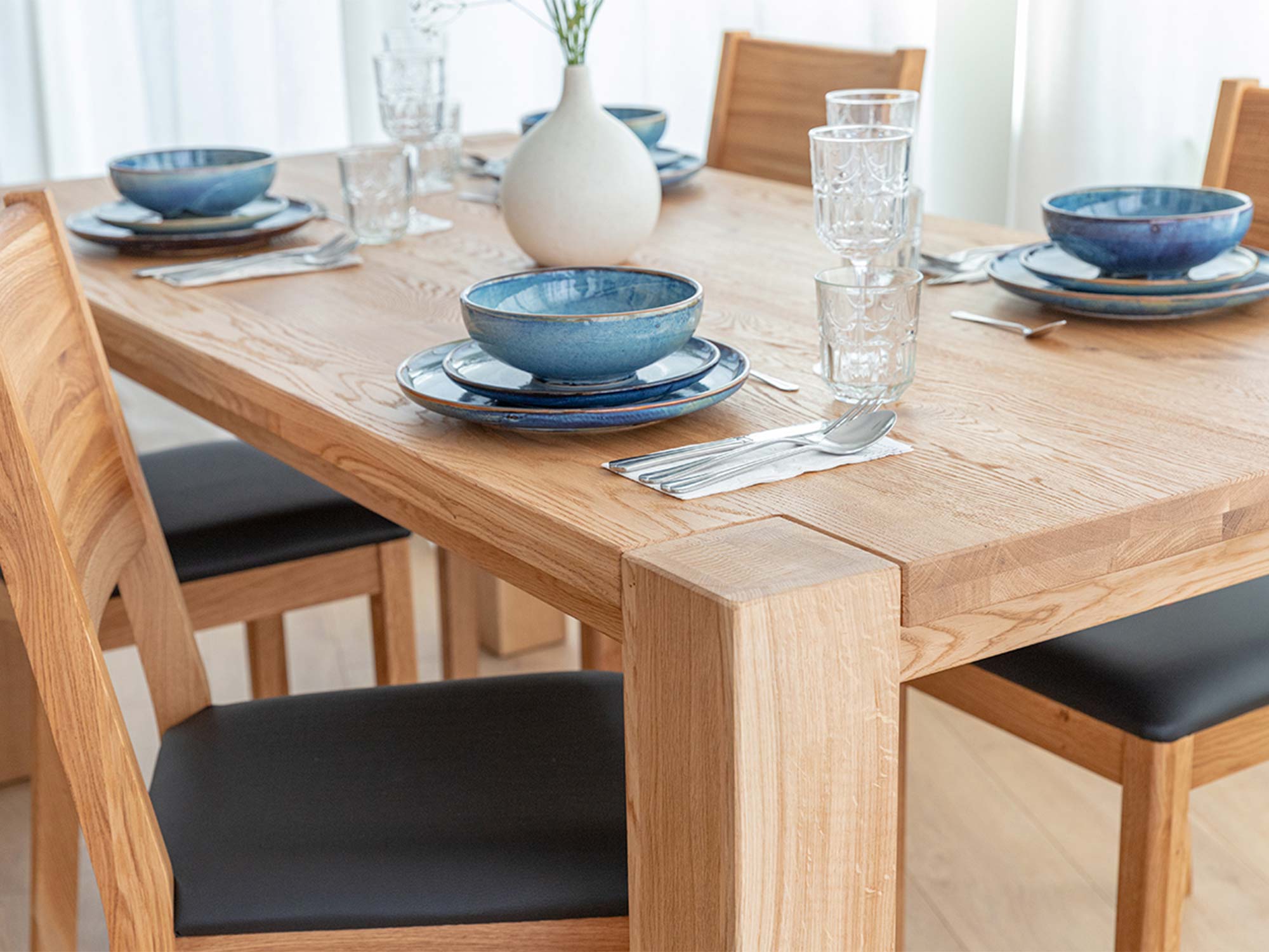 Detal narożnika blatu i nogi stołu drewnianego dębowego jasnego z zastawą