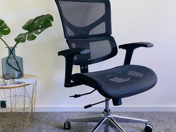 Černá ergonomická síťovaná kancelářská židle v interiéru, pohled z perspektivy