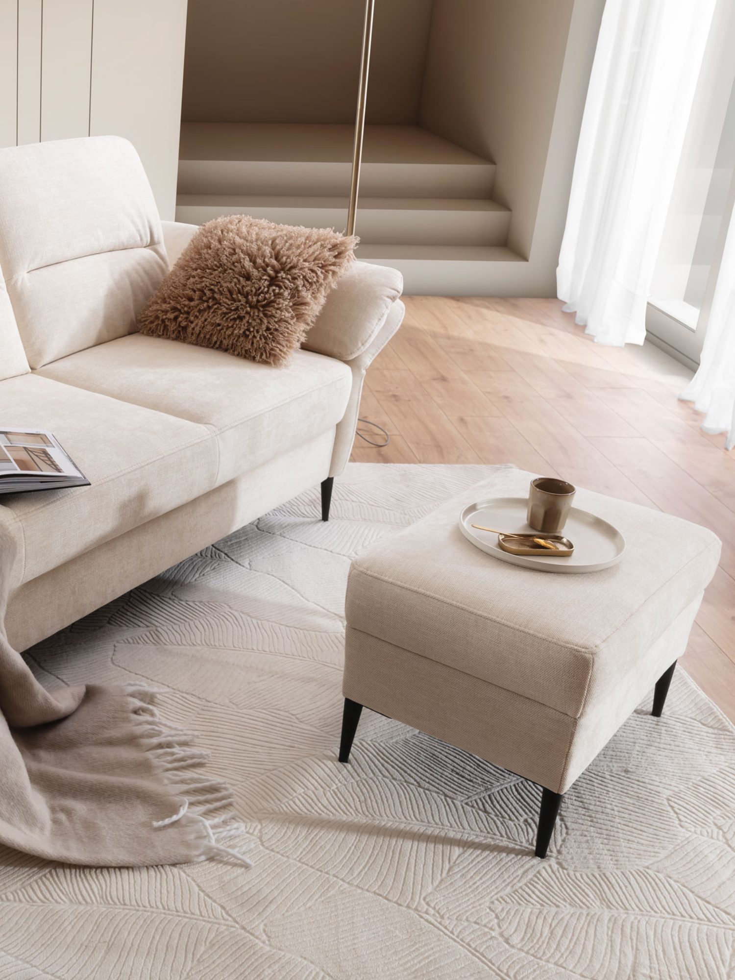 Taburet Narvento se světlým látkovým potahem v obývacím pokoji